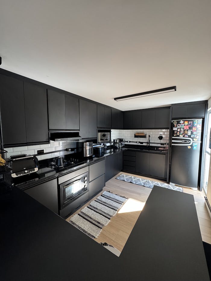 Contemporary black kitchen featuring appliances and sunlight. Ideal for cooking and home design concepts.